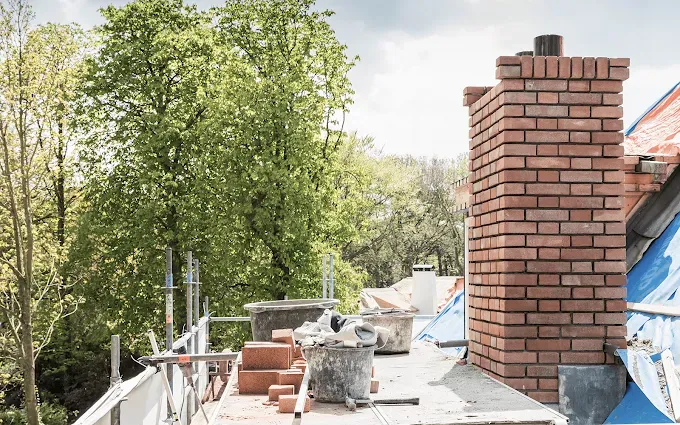 Chimney stack being repointed with fresh mortar and lead flashing